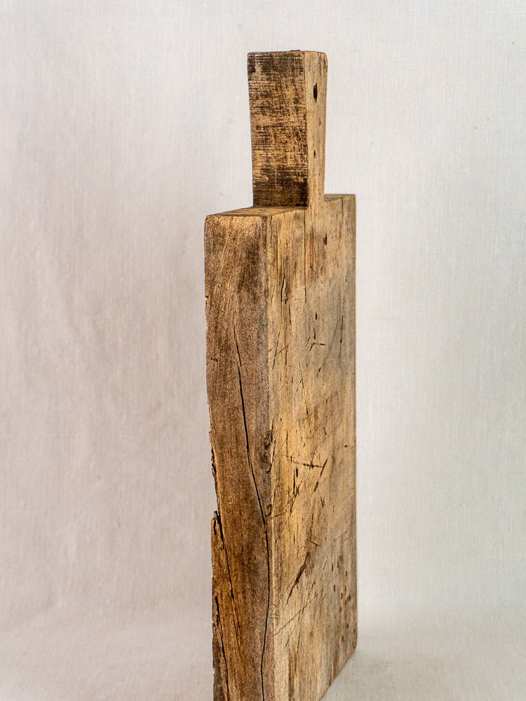 Antique French solid wood cutting board with handle, visible grain, cracks, and scratches.