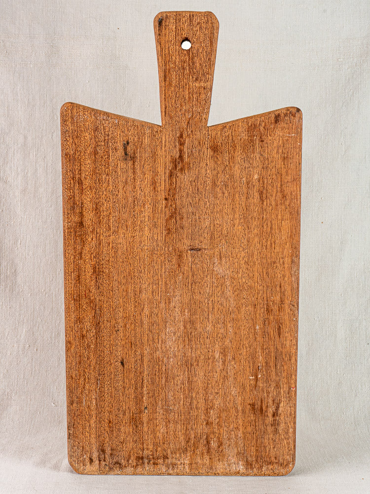 Antique French hardwood cutting board with classic rectangular shape, handle, and hanging hole against light background.