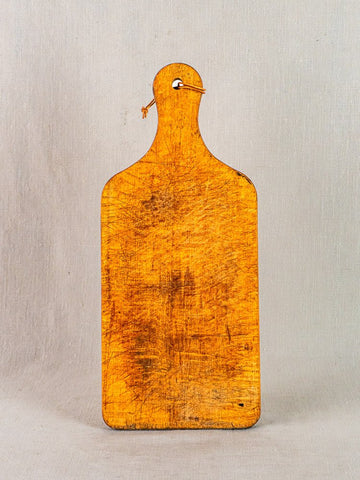 Antique French wooden cutting board with paddle handle and string, displayed upright on a plain background.