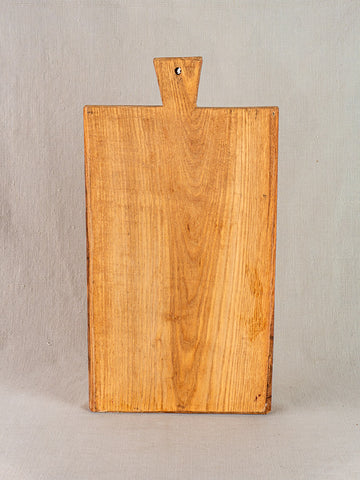 Antique French cutting board with carved paddle handle, early 20th century, displayed against light beige background.