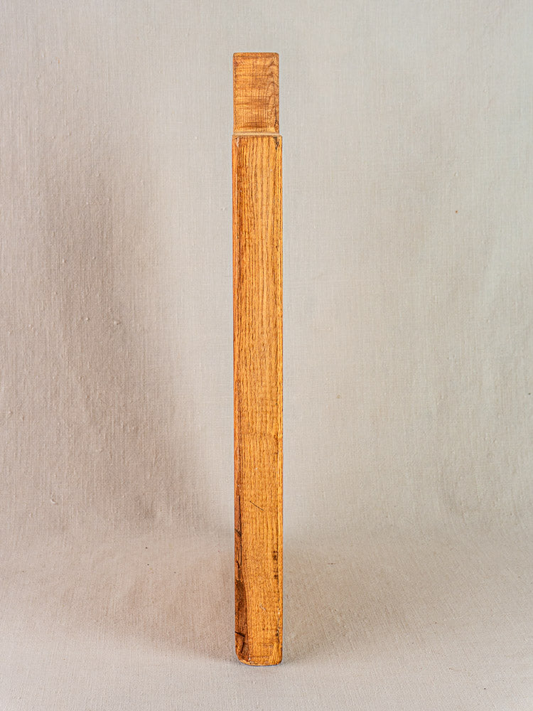 Early 20th century French antique cutting board with carved paddle handle, natural wood grain, neutral textured backdrop.