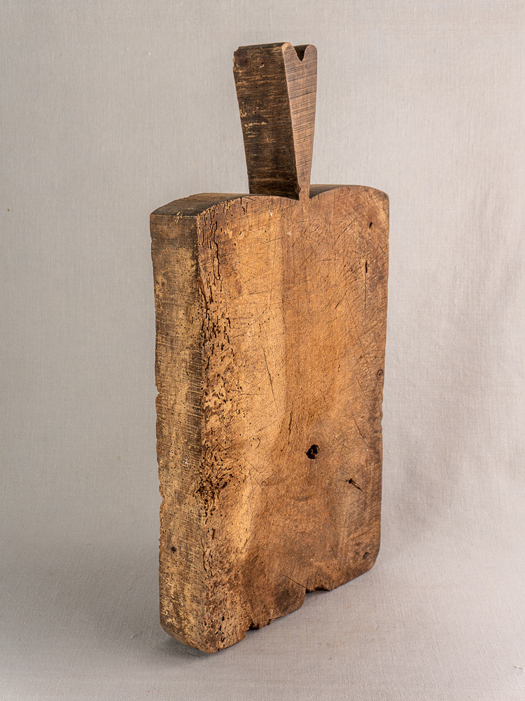 Antique French cutting board, 1880s, upright on neutral background, thick weathered wood, rectangular with carved handle notch.