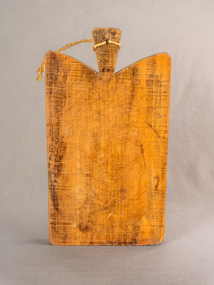 Antique French single plank cutting board, late 19th century, with rustic surface scratches, displayed upright on gray background.