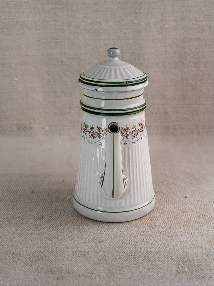 Antique French enamel coffee pot by B.B. Frères, circa 1910-20s, with floral garlands and green accents on neutral fabric background.