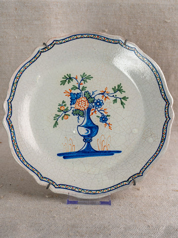 Antique French faience plate, c. 1850, scalloped edge, polychrome floral vase center, blue-orange border detailing.