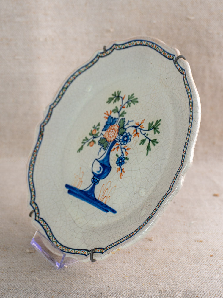Antique French faience plate, circa 1850, scalloped edges, hand painted floral bouquet in blue vase on display stand.