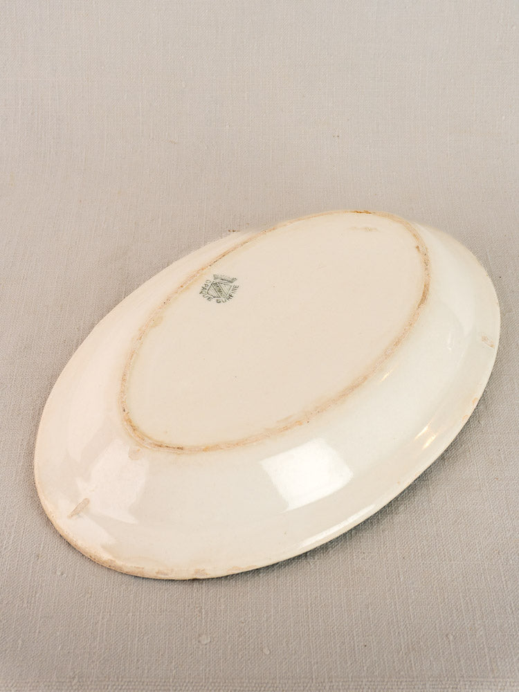 Antique French faience oval plate by Bertrand Opaque Surfine, base up with visible wear and maker’s stamp.