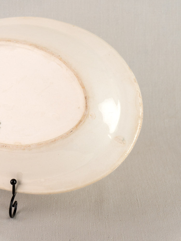 Antique French faience oval plate by Bertrand Opaque Surfine with blue flower basket, on black metal stand.