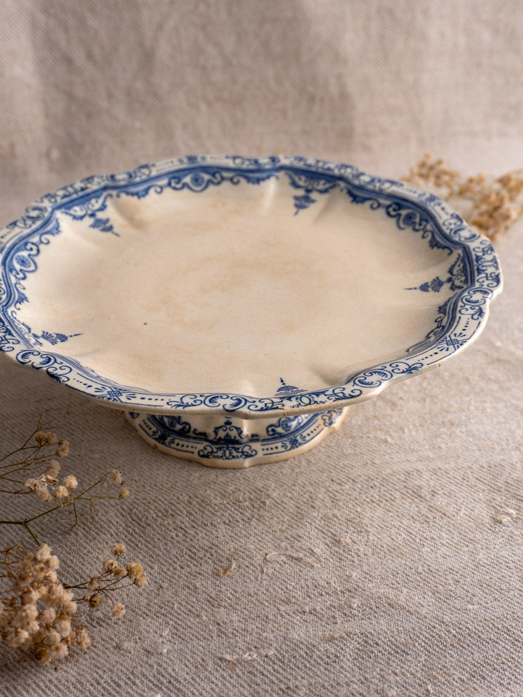 Antique French faience pedestal cake stand by E. Bourgeois, Paris, with blue floral rims on beige fabric with dried florals.