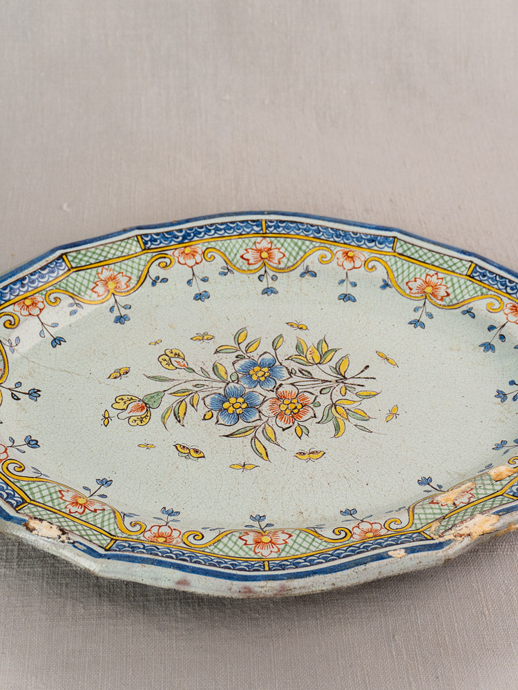 Antique French Orléans faience oval platter with blue, yellow, and green floral motifs, geometric borders, and age wear.