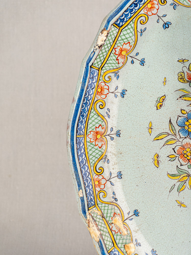 18th-century French Orléans faience platter with scalloped edge, polychrome floral motifs, crackle glaze, and subtle wear.