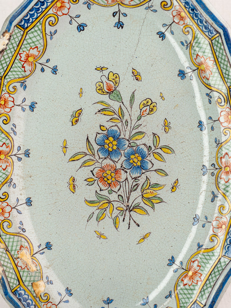 Antique 18th century French Orléans faience platter with polychrome floral bouquet and ornate border on pale ground.