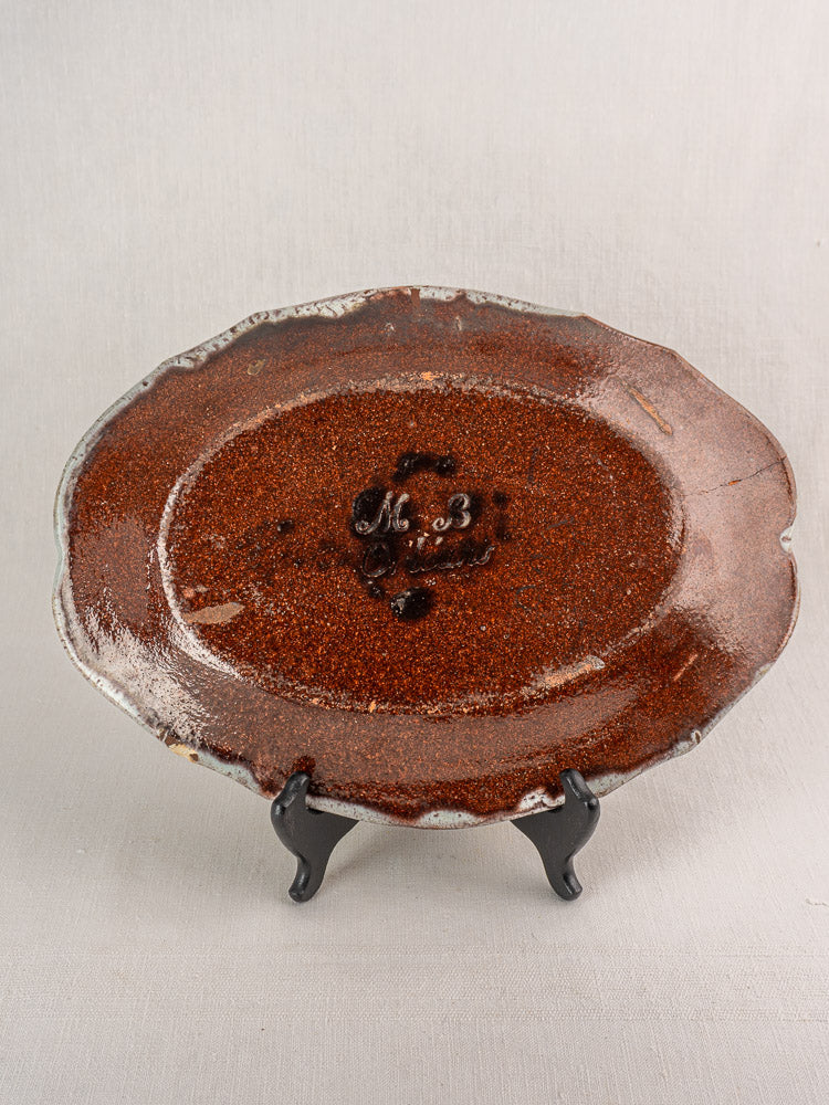 Antique 18th century French Orléans faience platter with polychrome cul noir glaze and "M. B." initials, on black stand.
