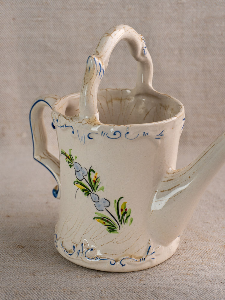 Vintage French faience watering can with hand-painted blue floral details and graceful curved handle.
