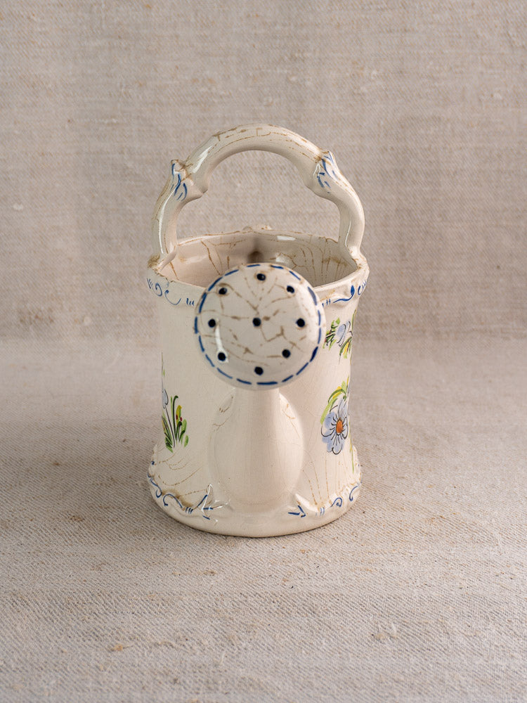 Vintage French faience watering can in cream ceramic with hand-painted blue and green floral motifs.