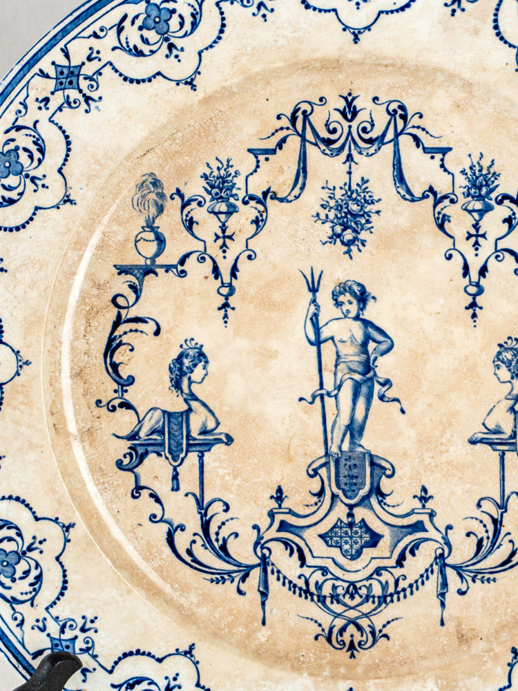 Antique French blue faience decorative plate with central cherub, busts, and ornate Moustiers-style patterns.