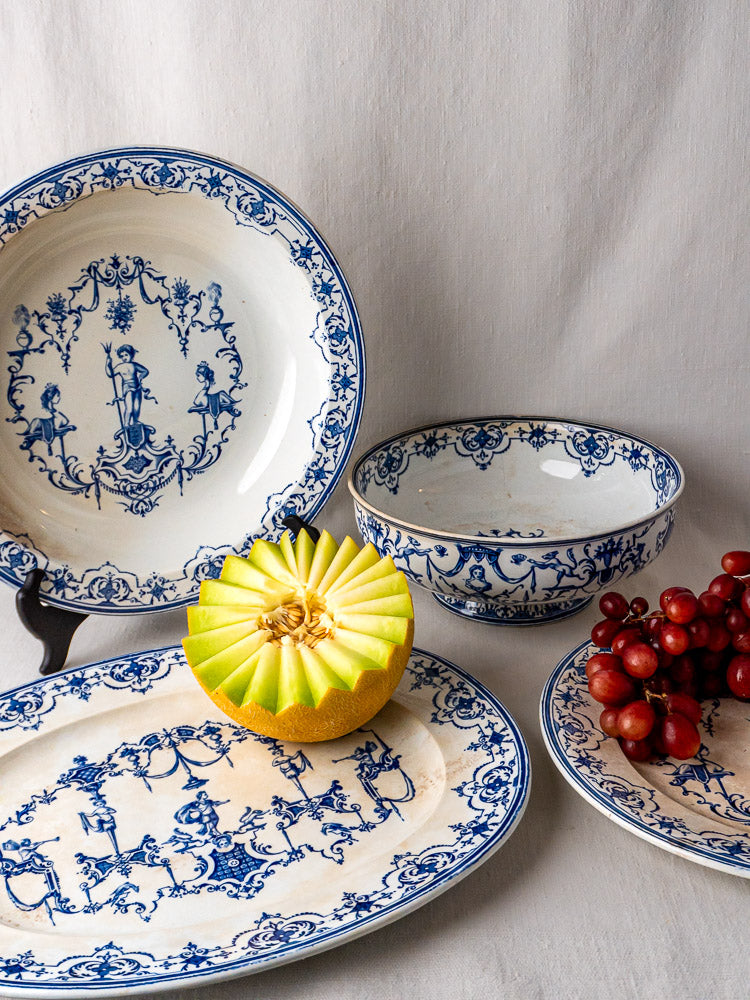 Jules Vieillard Bordeaux Moustiers Service faience pieces with blue and white patterns, on white cloth with grapes and melon.