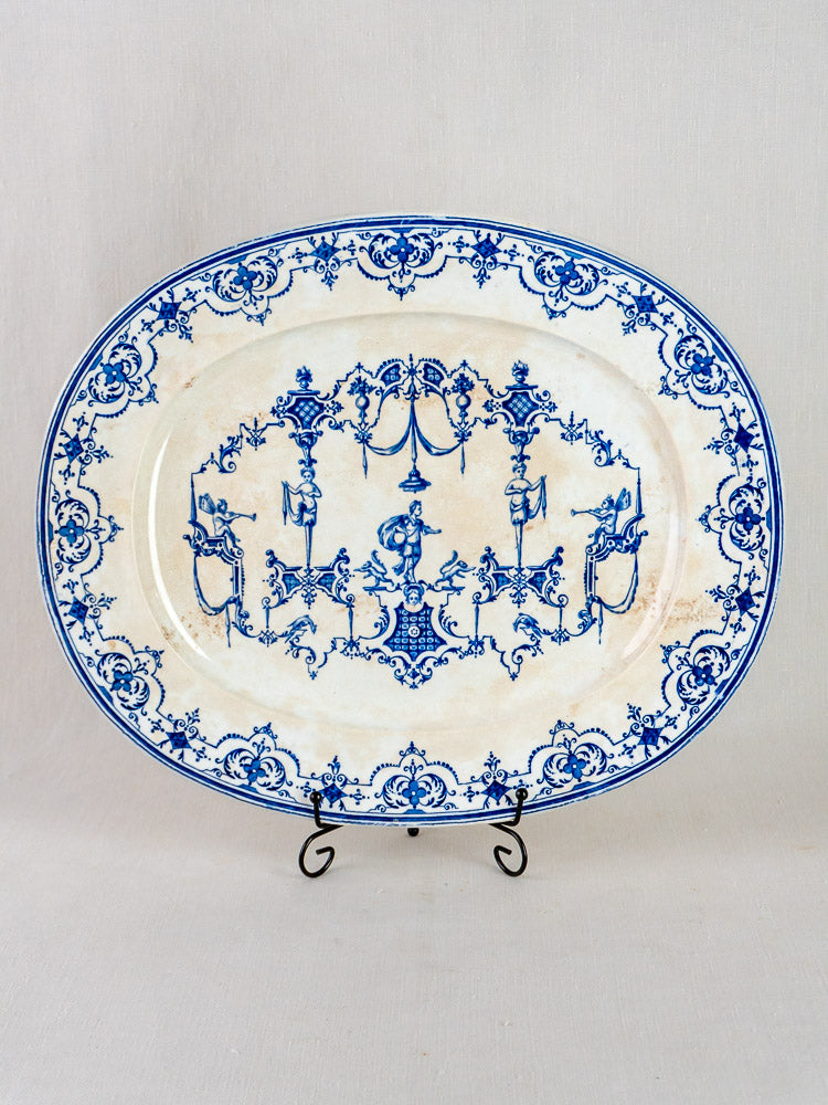 Antique French blue faience oval plate with intricate Moustiers-style floral and scroll design on stand.