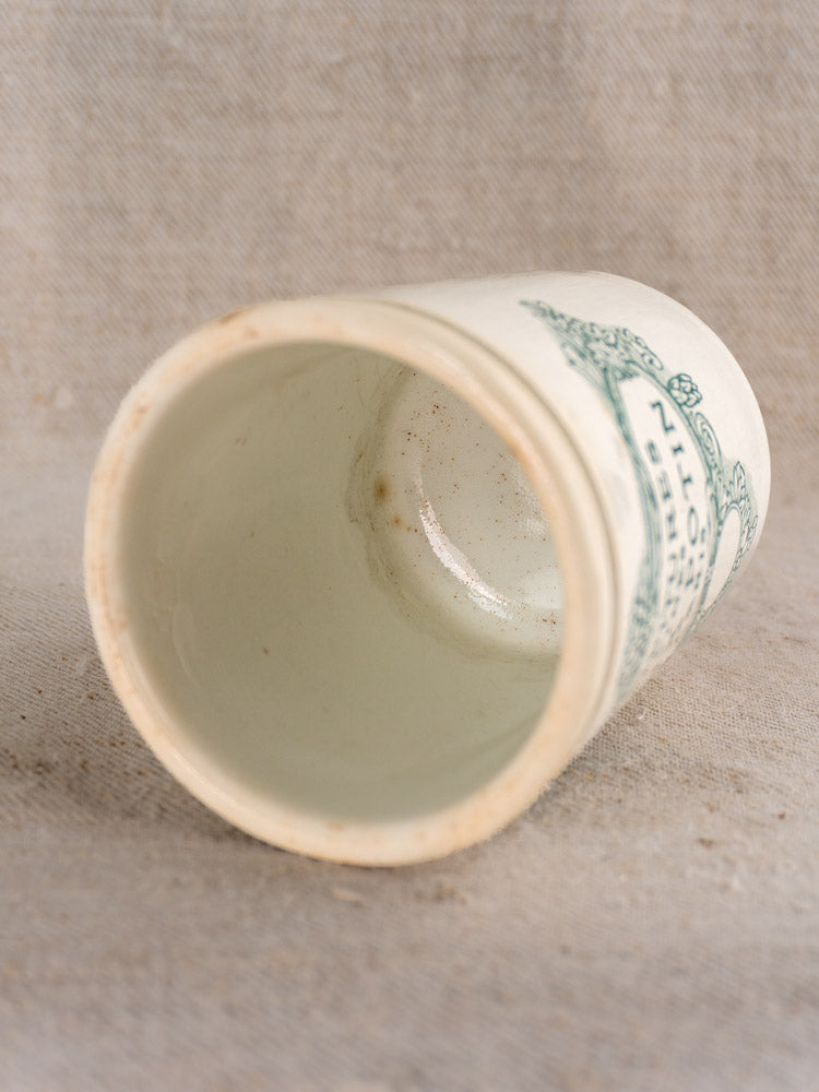 Antique French Felix Potin jam pot with green label, displayed on textured fabric showing interior and decorative exterior.