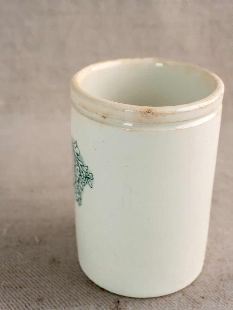 Antique French Felix Potin jam pot with subtle floral motif and rim stains on a textured beige surface.