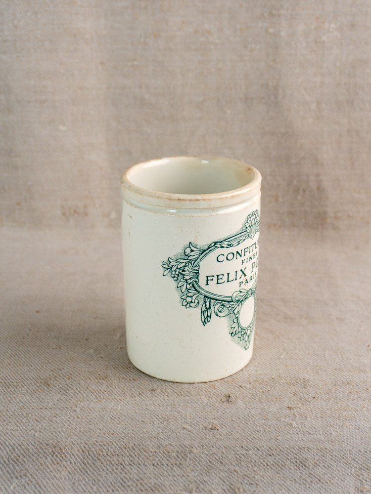 Antique French Felix Potin jam pot marked "Confitures Fines Paris," late 19th century, on beige textured fabric.