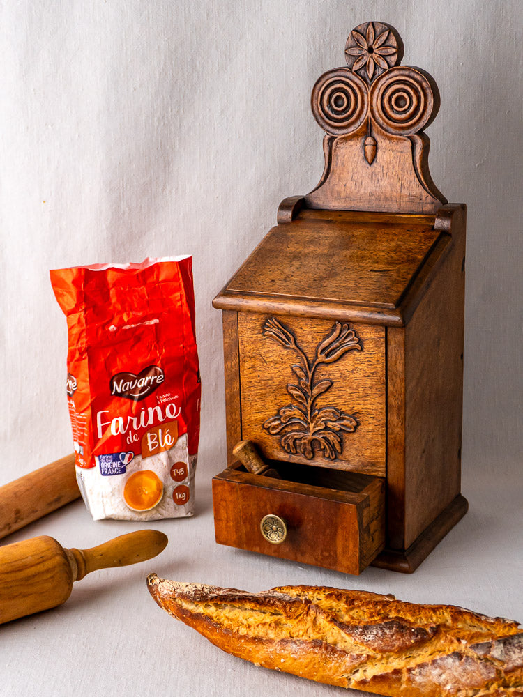 Antique French carved walnut flour and salt box with floral motif, small drawer, rolling pin, and baguette.