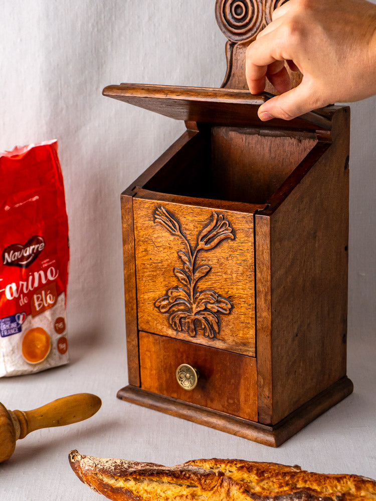 Antique carved walnut French flour and salt box with floral motif, baguette and rolling pin alongside.