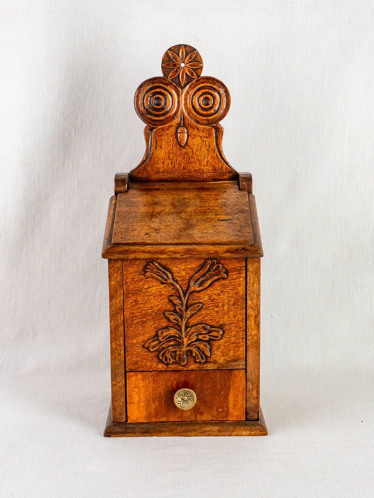 Antique French carved walnut flour and salt box with floral motif, round knob; plain white backdrop.