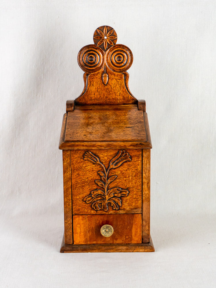 Antique French carved walnut flour and salt box with floral motif, round knob; plain white backdrop.