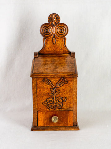 Antique French carved walnut flour and salt box with floral motif, round knob; plain white backdrop.