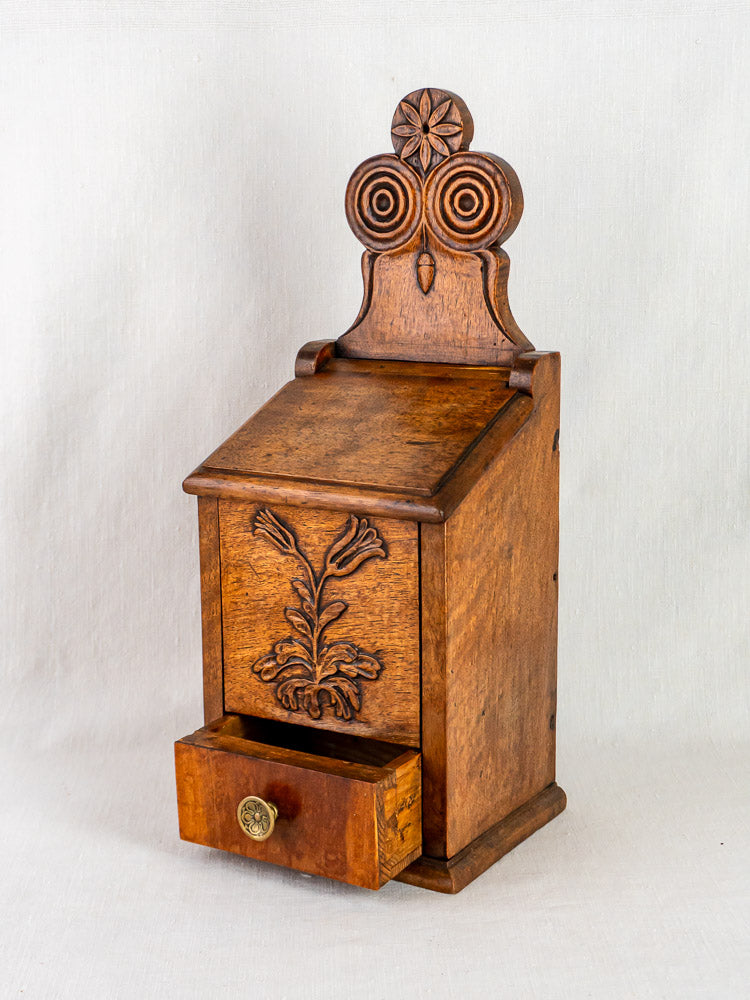 Antique French wall-mounted walnut flour and salt box with carved floral, spiral, and star motifs.