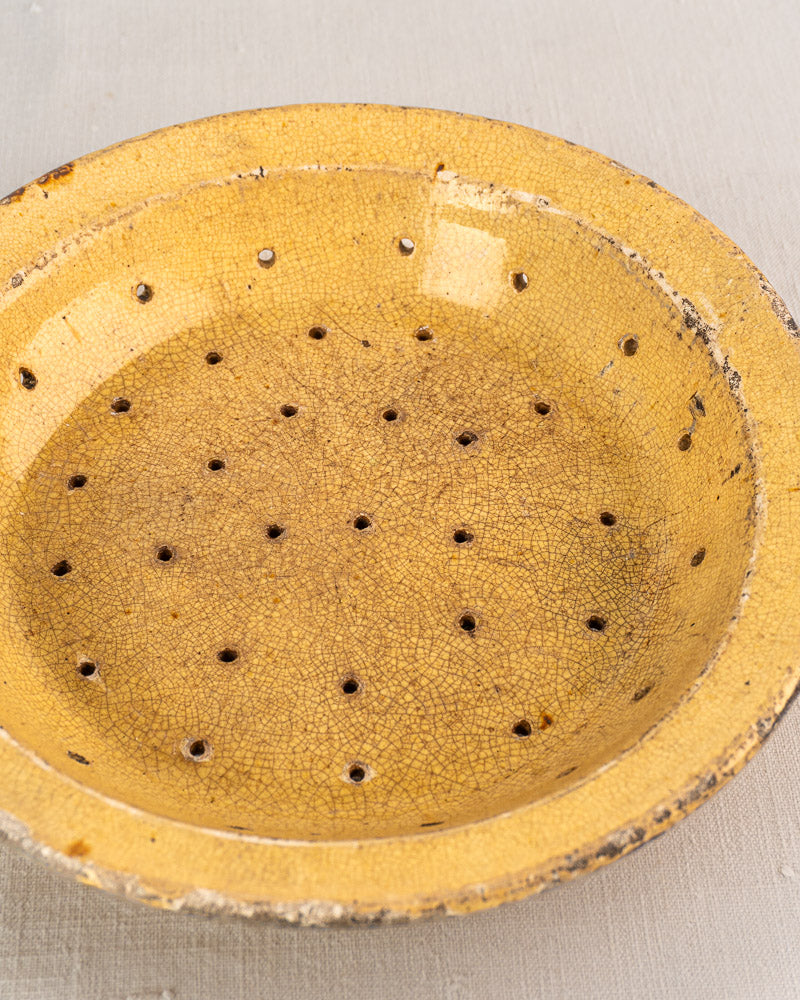 Antique French glazed earthenware fruit strainer with crackled yellow glaze and perforated bottom, 19th century pottery.