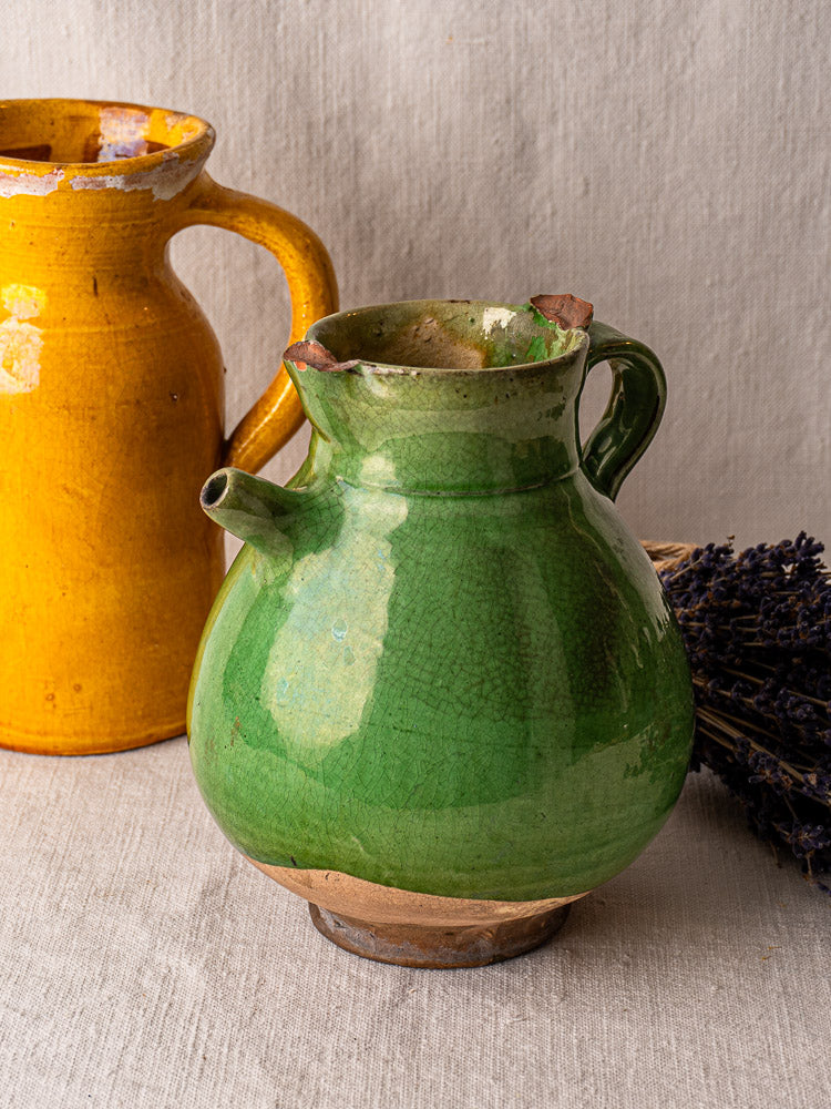 Antique French green glazed terracotta gargoulette water jug in front of yellow jug, dried lavender behind.