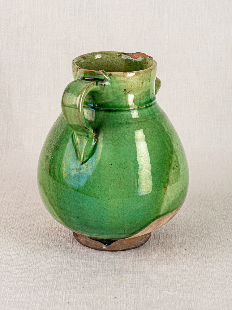 Antique French green-glazed terracotta gargoulette with round body, single handle, and chipped rim.