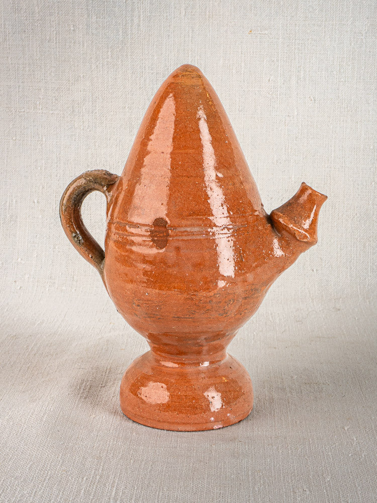 Antique French mammiforme terracotta jug with brown glaze, conical lid, and curved handle on light surface.