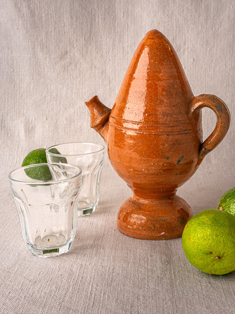 Antique French mammiforme terracotta jug with rich brown glaze, tall lid, handle, and spout on neutral surface.