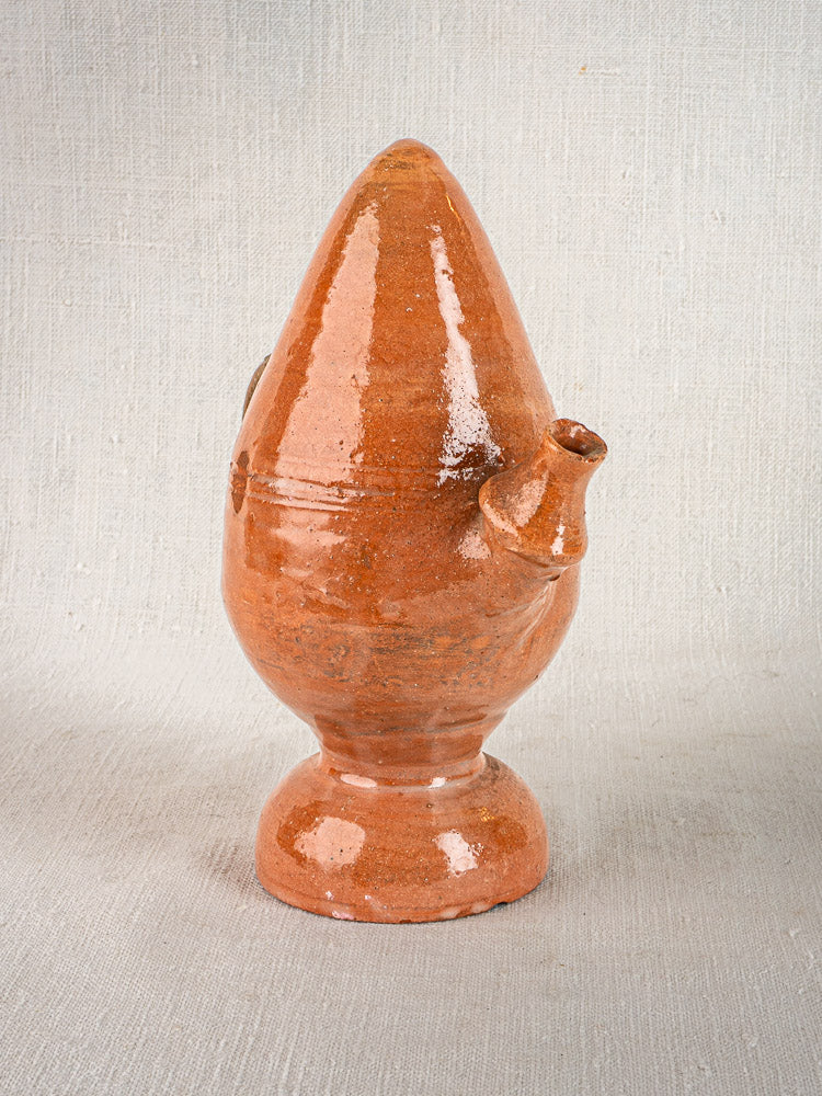 Antique French mammiforme glazed terracotta jug with glossy brown finish, conical top, and side spout on fabric background.