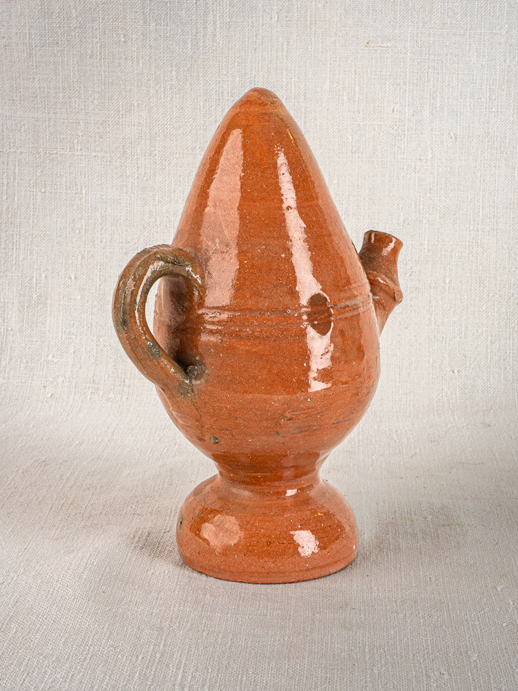 Glossy reddish-brown glazed terracotta French mammiforme jug with pointed top, handle, and spout on round base.