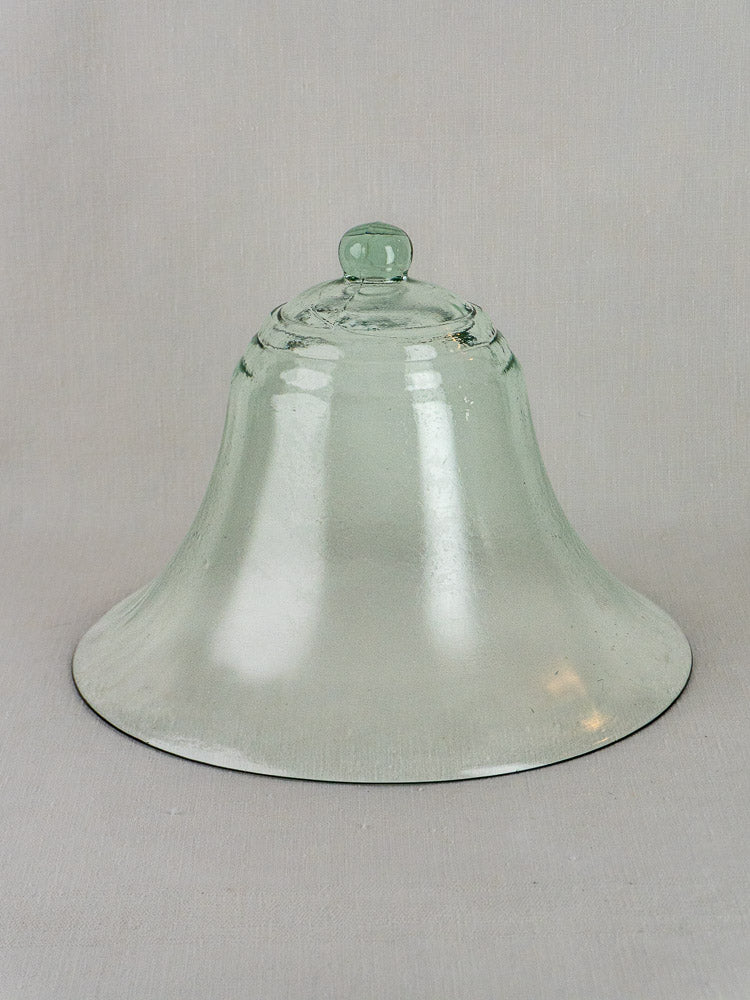 Antique French hand-blown glass cloche from the 19th century with bell-shaped form and knob, set on a light gray background.