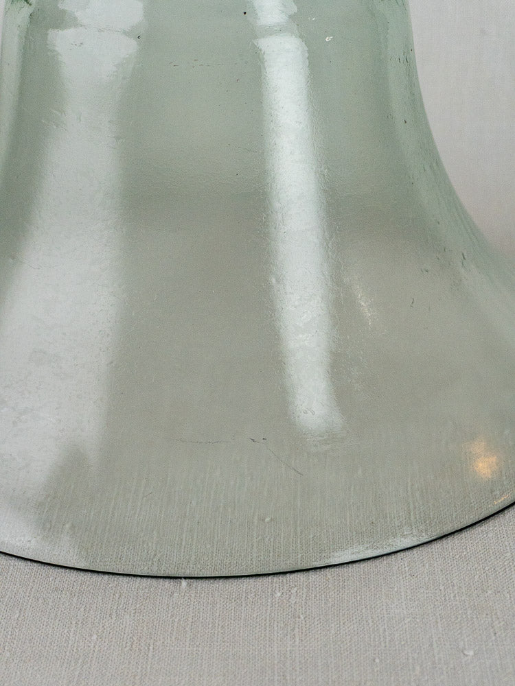 Antique French hand blown glass cloche base in light green, detailed reflections on fabric background.