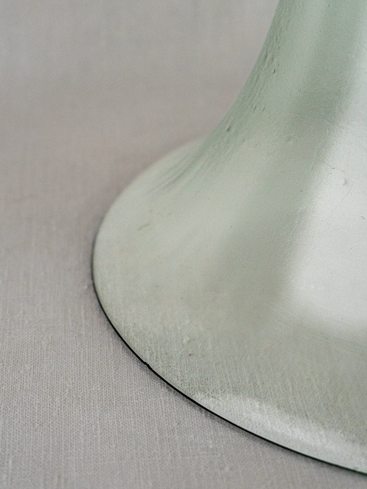 Antique French hand-blown glass cloche base resting on a textured light surface.