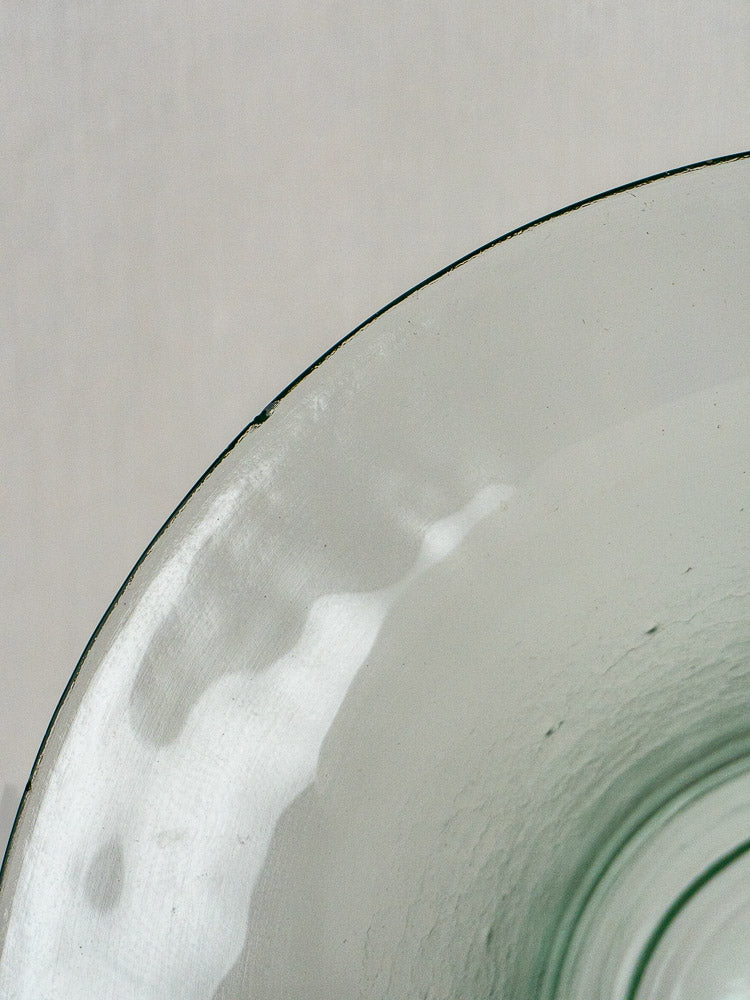 Antique French hand blown glass cloche with green tint and wavy texture on neutral background.