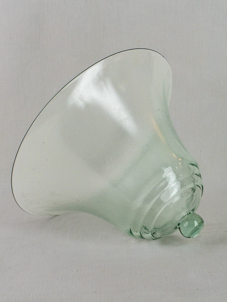 Large hand blown 19th-century French glass cloche with rounded handle on light gray surface.