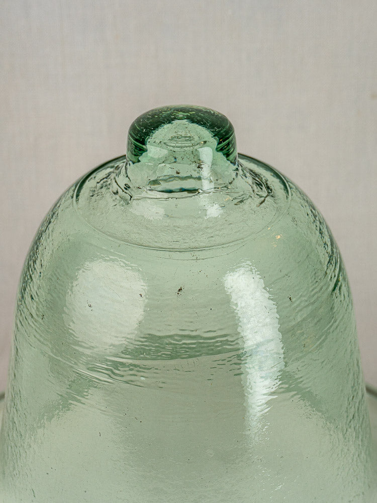 Antique French hand-blown glass garden cloche with green-tinted dome and rounded knob, textured lines visible.