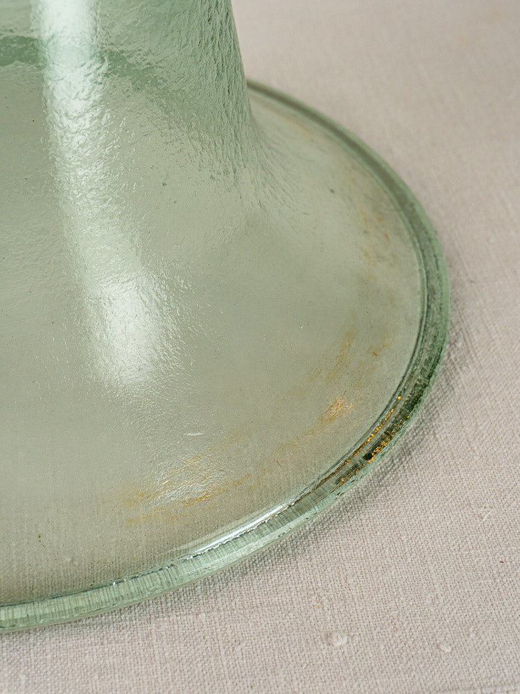 Antique French hand-blown glass garden cloche base with green tint and subtle edge discoloration on beige fabric.