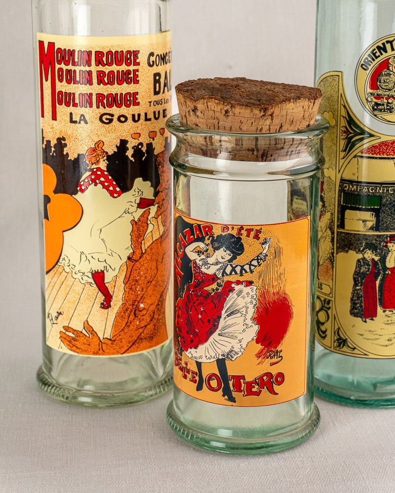 Set of five vintage French glass jars with Belle Époque-style illustrated labels and cork stoppers.