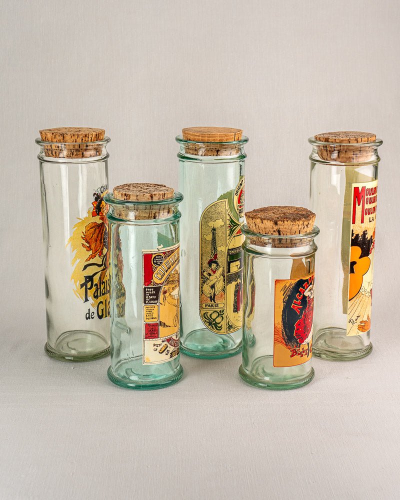 Set of five vintage French glass jars with cork stoppers and 1970s Belle Époque poster labels.