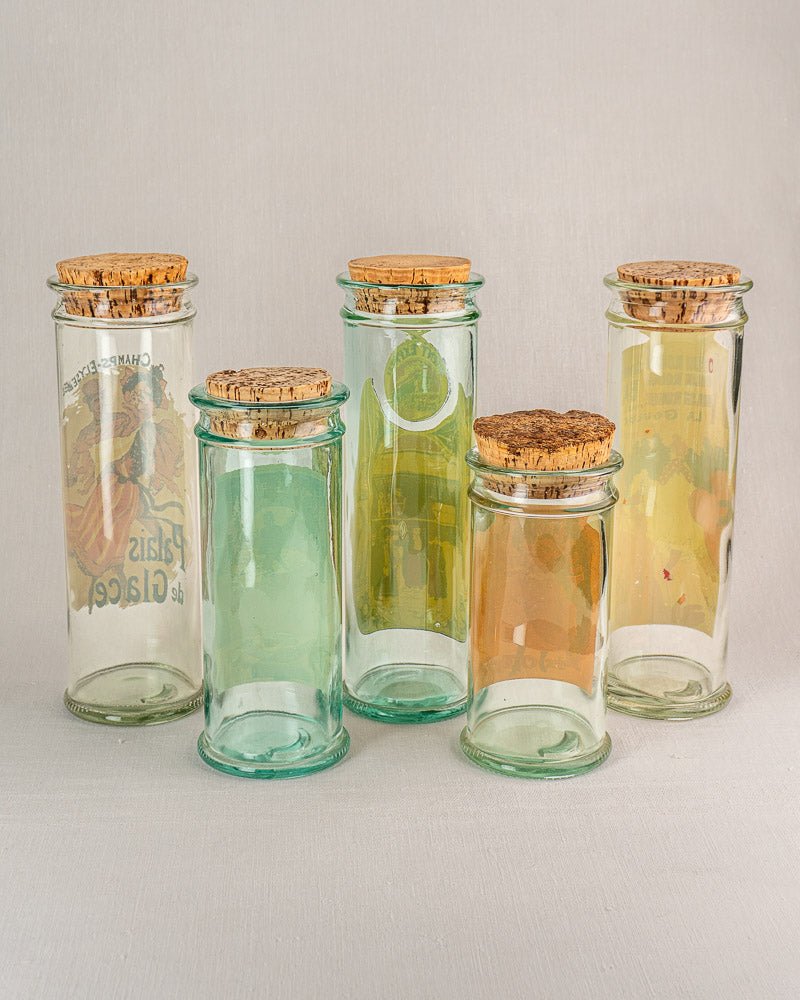 Set of five vintage French glass jars with cork stoppers and subtle tinted labels.