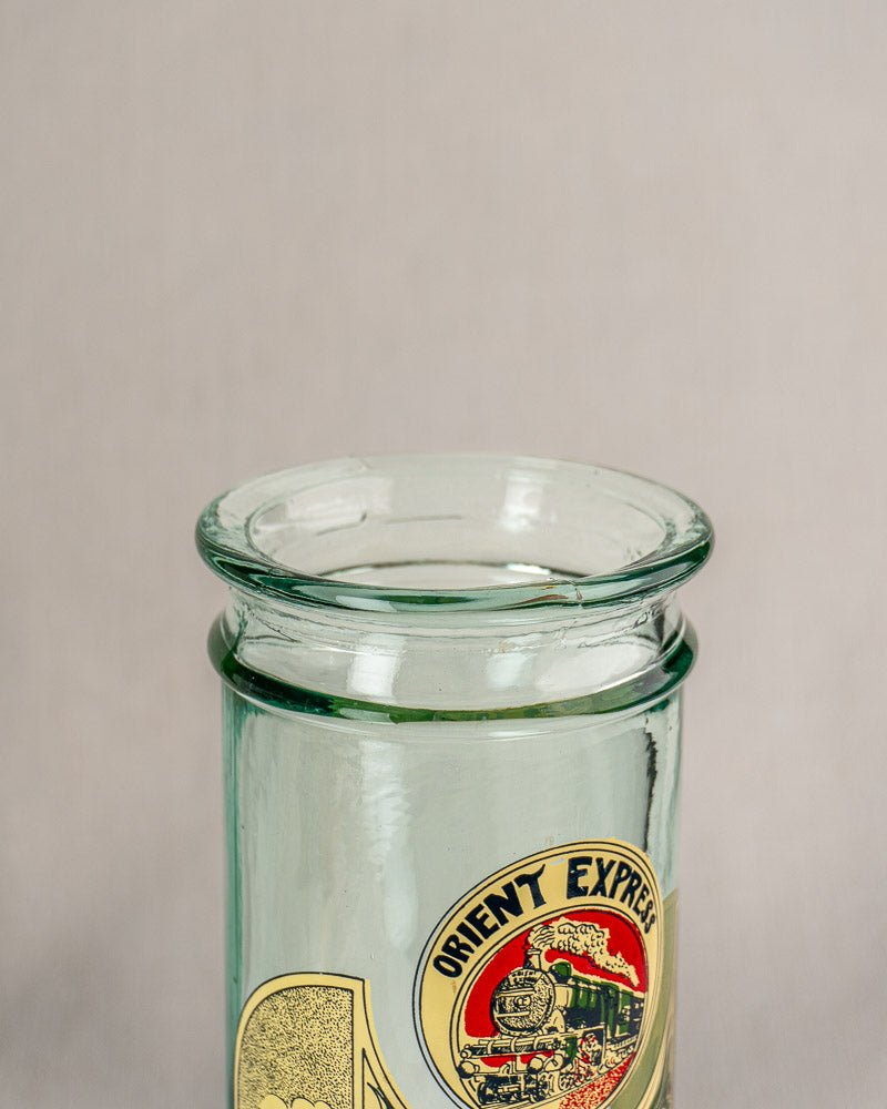 Vintage French glass jar with cork stopper, Belle Époque Orient Express label, neutral background.