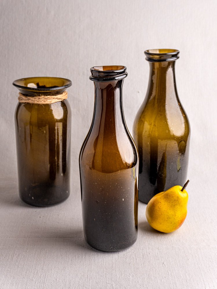 Set of three 19th century antique French hand blown glass truffle jars with twine accent, beside pear.
